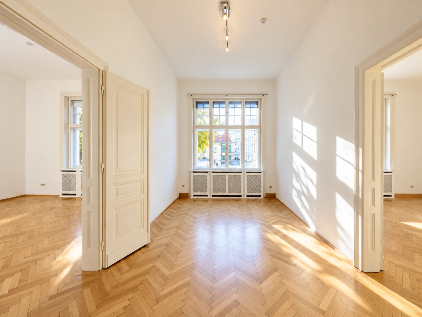 Sanierte Wohnung in der Böcklinstraße in Wien mit offenen Flügeltüren, hohen Fenstern und Fischgrätparkett