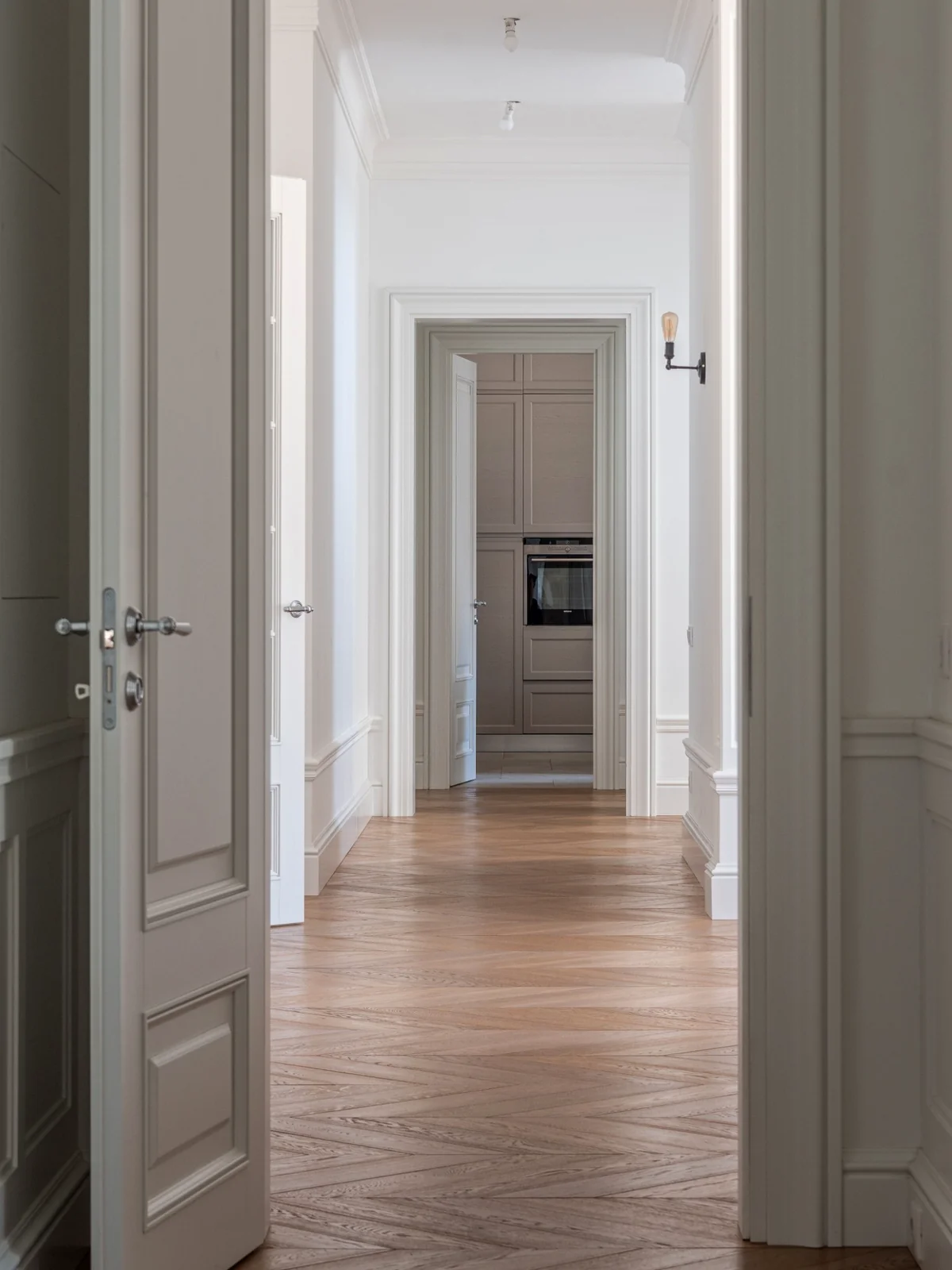 Eleganter Altbau-Flur mit aufeinanderfolgenden Türrahmen, hohen Decken und Parkettboden