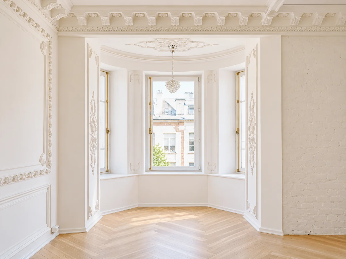 Heller sanierter Altbauraum mit aufwendigen Stuckverzierungen, großem Erkerfenster und Parkettboden